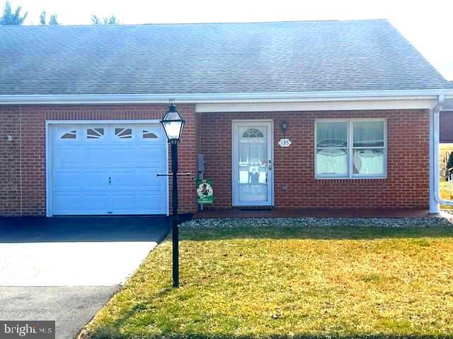 view of front facade featuring roof with shingles, brick siding, an attached garage, driveway, and a front lawn