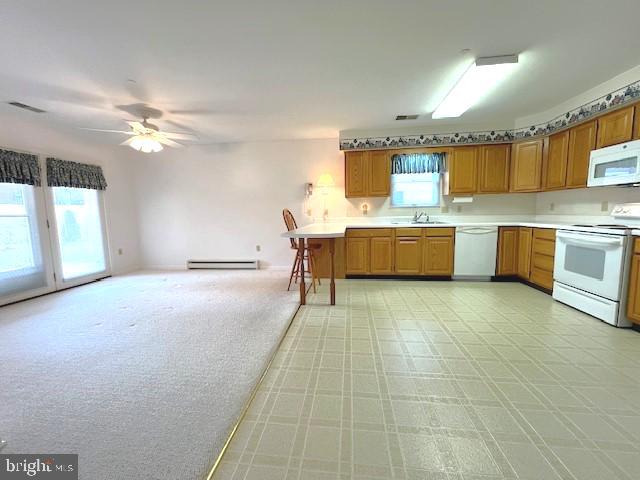 kitchen featuring light countertops, white appliances, baseboard heating, and brown cabinetry