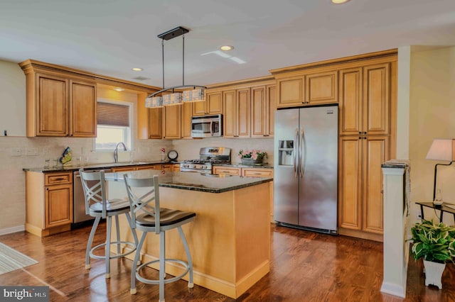 kitchen featuring dark wood-style floors, stainless steel appliances, a sink, and a center island