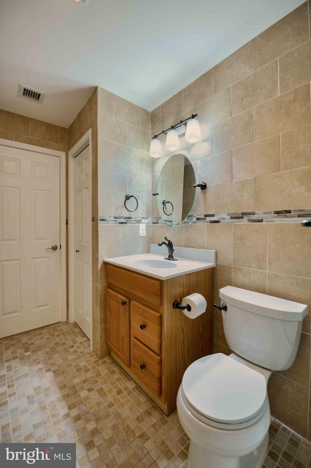 bathroom with visible vents, toilet, tile walls, and vanity