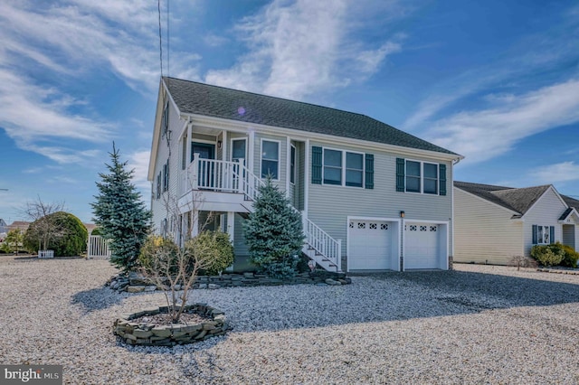 view of front of home with driveway, covered porch, an attached garage, and stairs