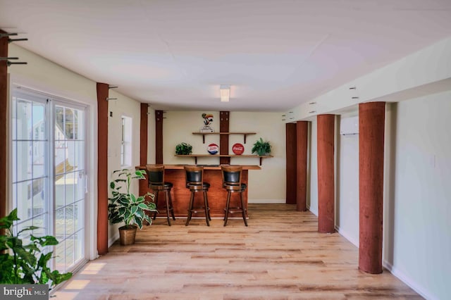 interior space featuring light wood finished floors, a bar, and baseboards