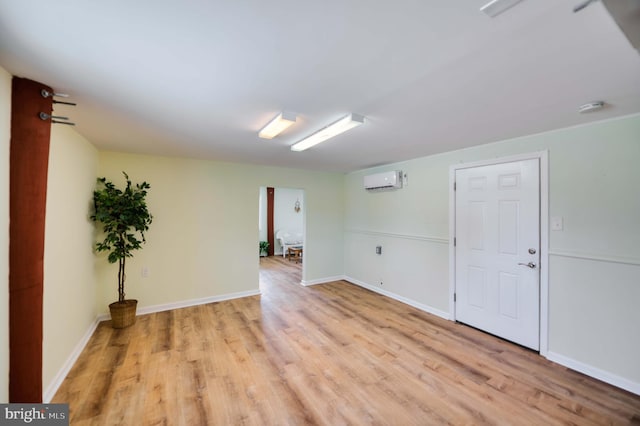 unfurnished room with baseboards, a wall mounted air conditioner, and light wood-style floors