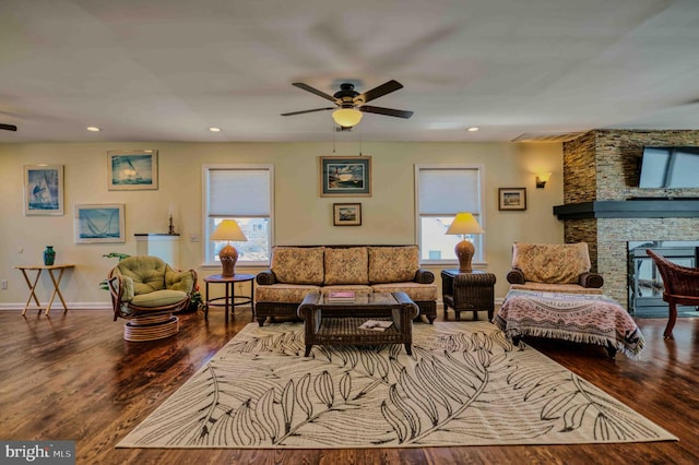 living room with recessed lighting, ceiling fan, a stone fireplace, wood finished floors, and baseboards