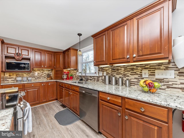 kitchen with light stone counters, a sink, stainless steel appliances, light wood-type flooring, and backsplash