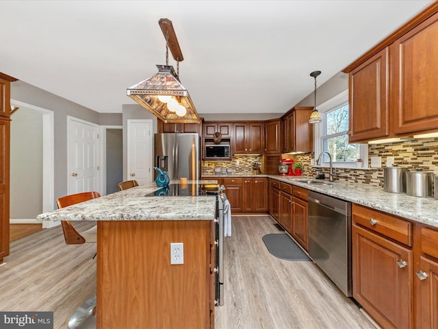 kitchen featuring a sink, stainless steel appliances, a kitchen bar, and light wood-style floors