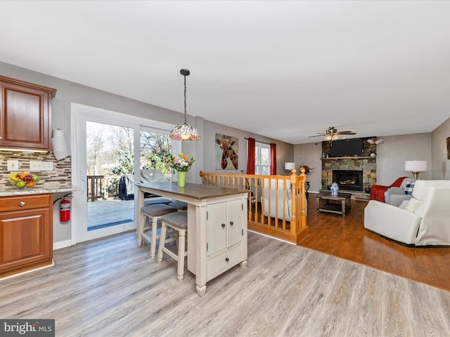 kitchen featuring light wood finished floors, decorative backsplash, a healthy amount of sunlight, and a fireplace