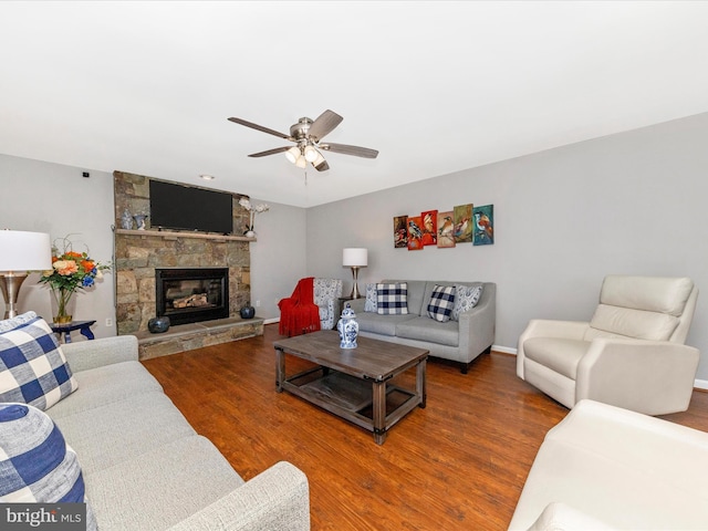 living area with baseboards, a ceiling fan, wood finished floors, and a fireplace