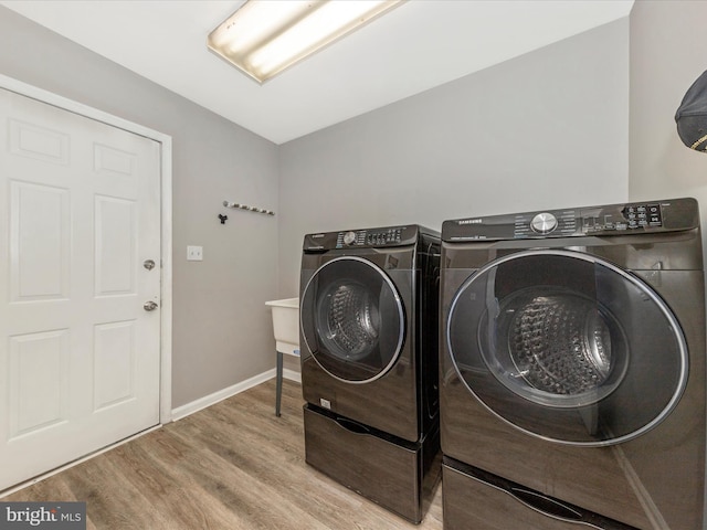 laundry area with laundry area, wood finished floors, baseboards, and washing machine and clothes dryer