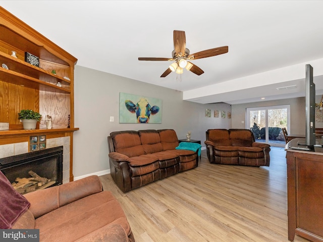 living area with visible vents, baseboards, light wood-style flooring, a fireplace, and ceiling fan