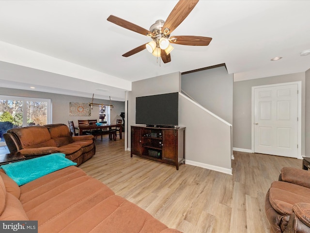 living room featuring ceiling fan, stairs, baseboards, and wood finished floors