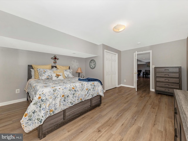 bedroom featuring wood finished floors, baseboards, and a closet