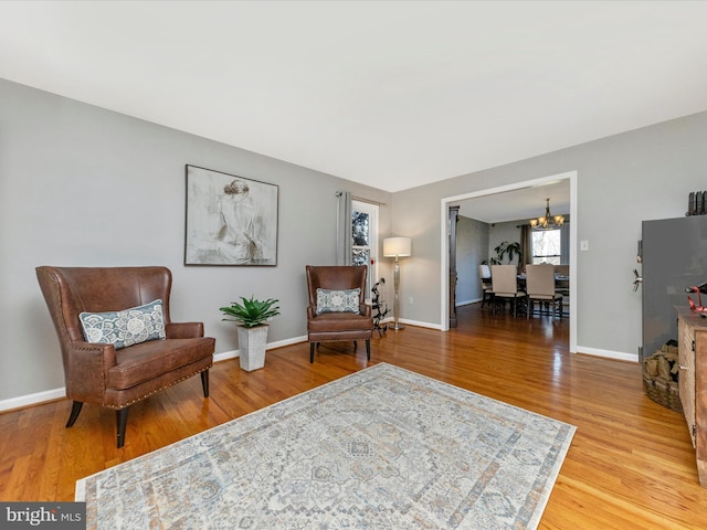 sitting room with baseboards, a notable chandelier, and wood finished floors