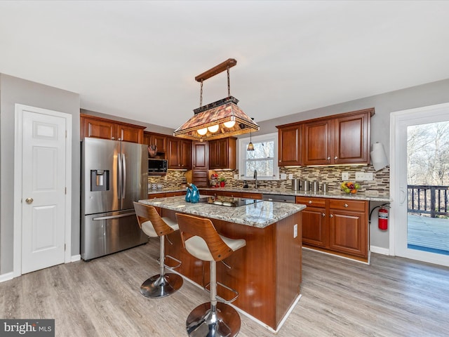 kitchen featuring light stone counters, light wood-type flooring, appliances with stainless steel finishes, and decorative backsplash