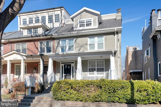 multi unit property featuring covered porch and brick siding