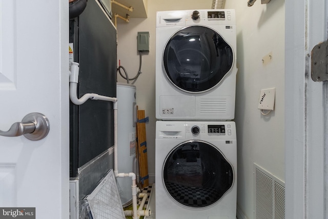 clothes washing area with laundry area, visible vents, stacked washing maching and dryer, and water heater