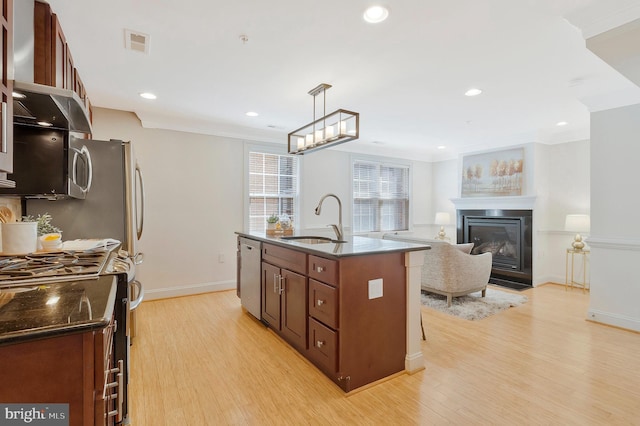 kitchen featuring visible vents, a glass covered fireplace, appliances with stainless steel finishes, light wood-type flooring, and a sink