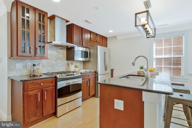 kitchen featuring a sink, visible vents, appliances with stainless steel finishes, wall chimney range hood, and tasteful backsplash