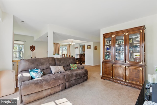 living room with a notable chandelier, visible vents, and light carpet