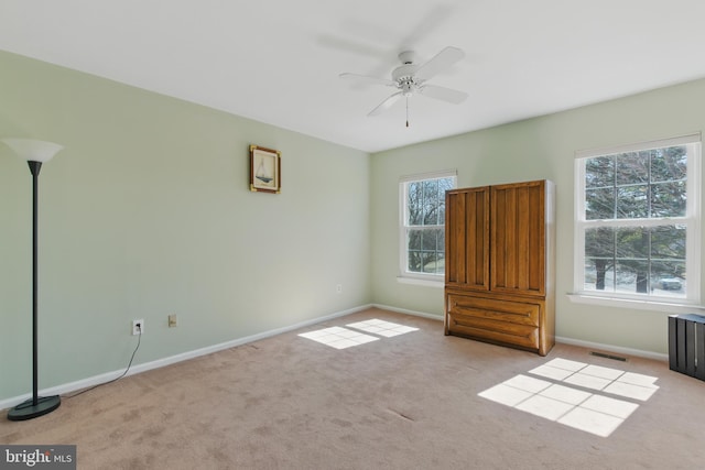 carpeted spare room with a ceiling fan, baseboards, and visible vents