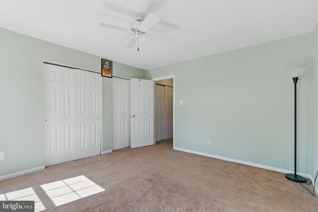 unfurnished bedroom with a ceiling fan, baseboards, multiple closets, and carpet floors