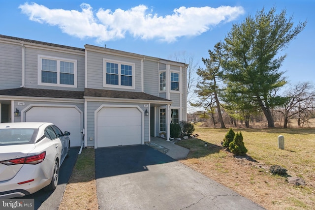 view of property featuring a garage, a front lawn, and driveway