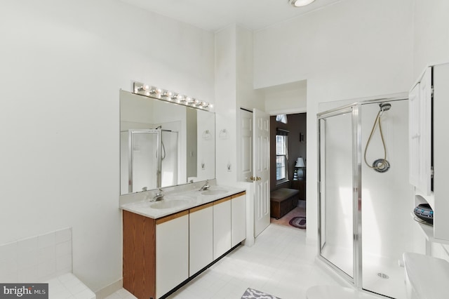 full bath featuring a shower stall, a high ceiling, double vanity, and a sink