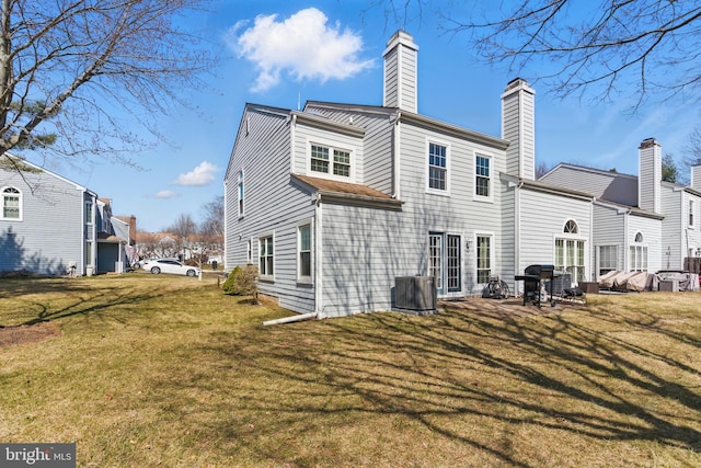 rear view of house with a yard, a chimney, and central AC