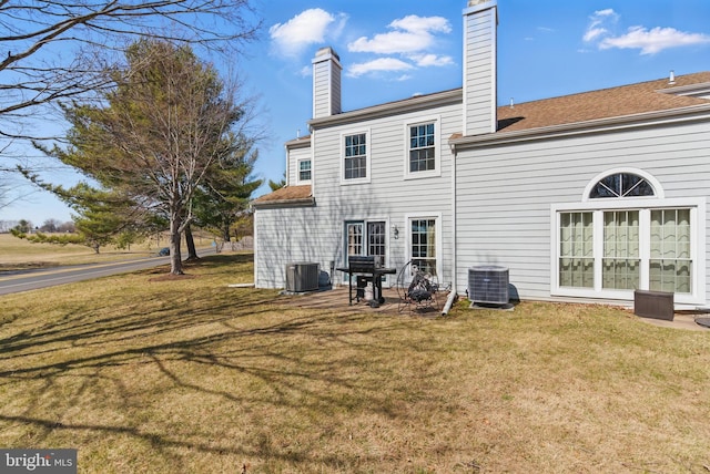 back of house with a patio, cooling unit, a lawn, and a chimney