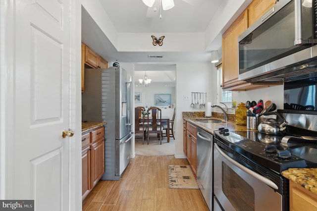 kitchen with visible vents, light wood-type flooring, brown cabinets, stainless steel appliances, and a sink