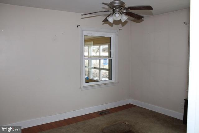 spare room with baseboards, a ceiling fan, and wood finished floors