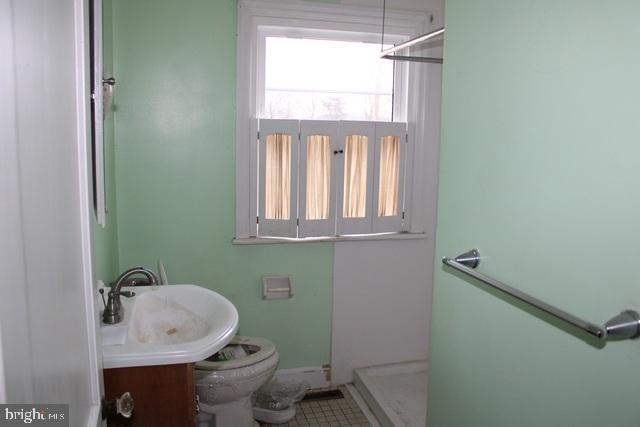 bathroom with a shower, tile patterned flooring, vanity, and toilet