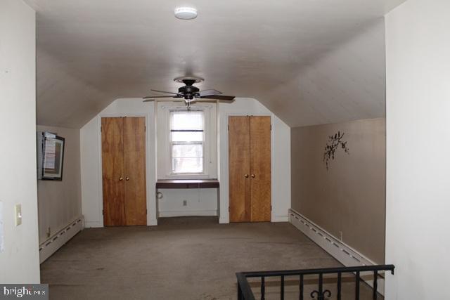 additional living space with carpet floors, a baseboard radiator, vaulted ceiling, and a ceiling fan