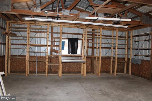 misc room featuring concrete flooring, metal wall, and lofted ceiling