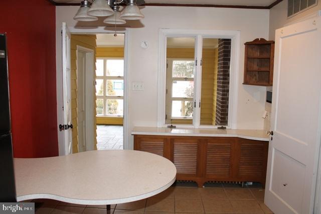 unfurnished dining area featuring visible vents, crown molding, and tile patterned floors