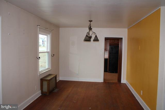 unfurnished dining area featuring baseboards and wood finished floors