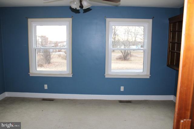 interior space with ceiling fan, carpet floors, visible vents, and baseboards