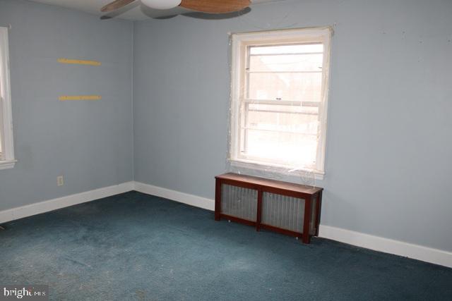 unfurnished room featuring radiator heating unit, a wealth of natural light, and carpet flooring