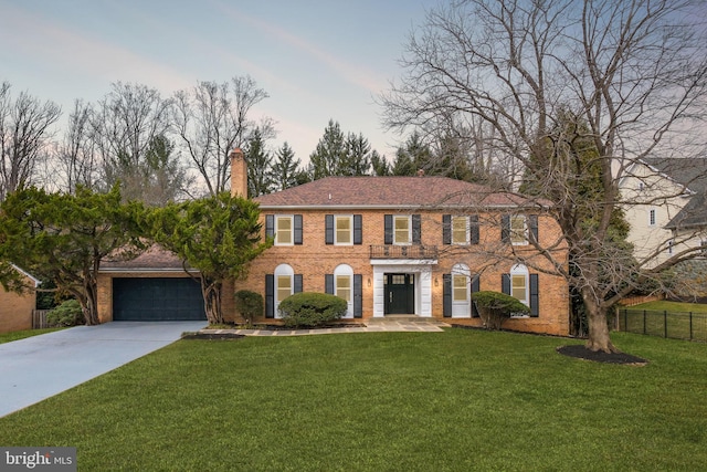 view of front facade featuring driveway, a chimney, fence, a front yard, and brick siding