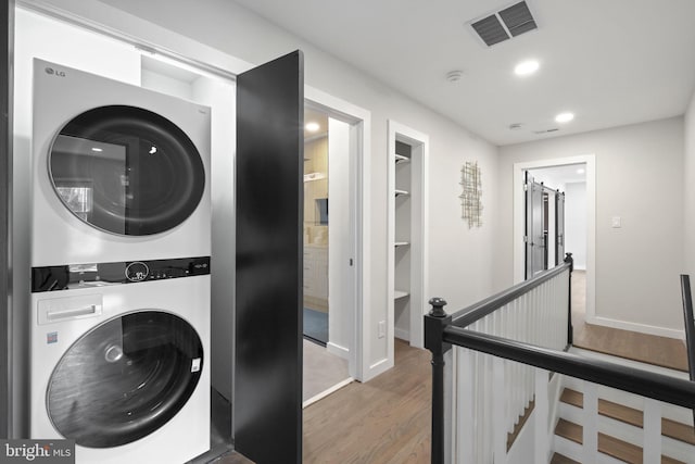 laundry area featuring recessed lighting, laundry area, wood finished floors, visible vents, and stacked washer / drying machine