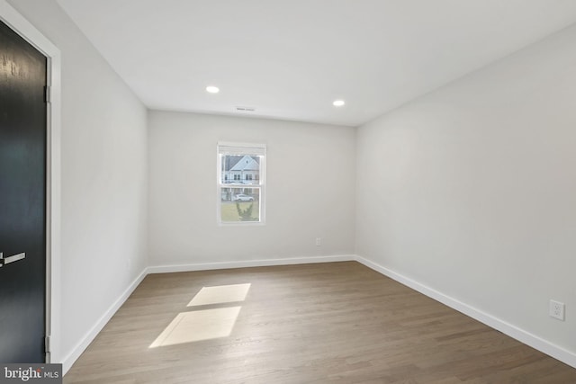 spare room with recessed lighting, wood finished floors, visible vents, and baseboards