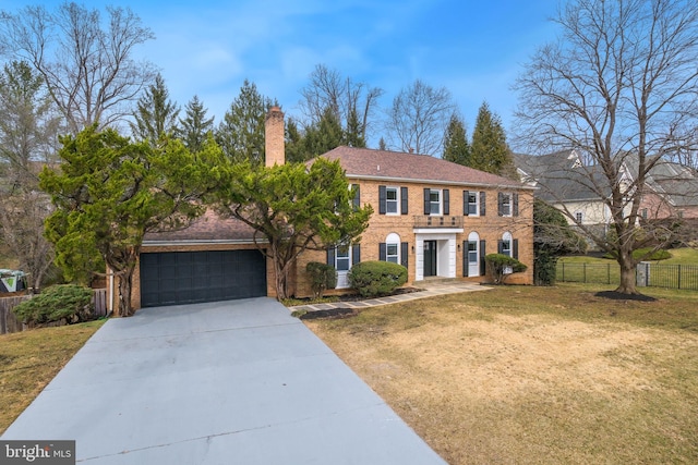 view of front of house featuring brick siding, a chimney, concrete driveway, fence, and a front lawn