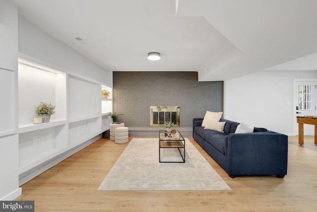 living area with a brick fireplace and light wood-style flooring