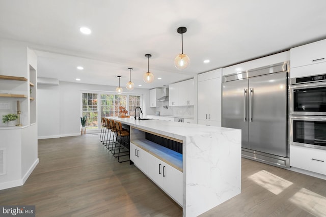 kitchen with modern cabinets, appliances with stainless steel finishes, white cabinets, a sink, and wood finished floors