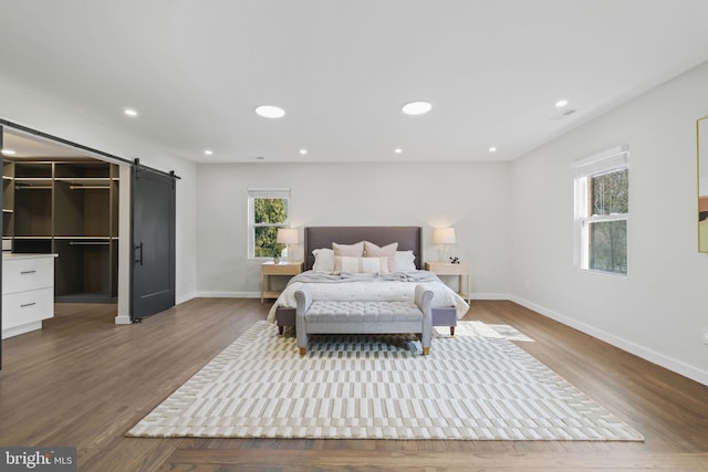 bedroom featuring baseboards, a barn door, wood finished floors, and recessed lighting