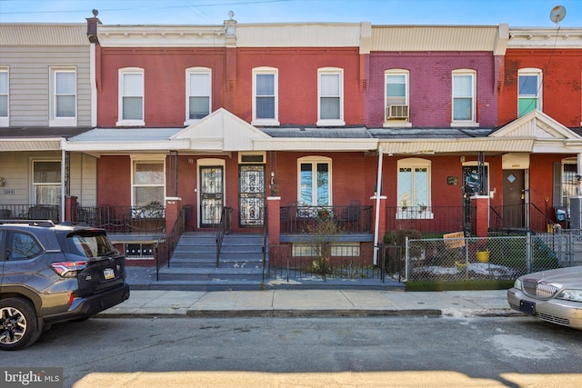 multi unit property with a fenced front yard, a porch, and brick siding