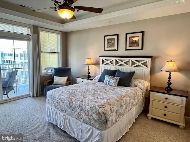 bedroom with carpet flooring, visible vents, access to exterior, a tray ceiling, and crown molding