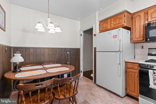 kitchen featuring range with gas cooktop, light countertops, freestanding refrigerator, wainscoting, and black microwave