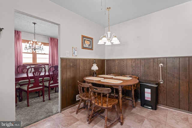 dining area featuring a chandelier, a wainscoted wall, wooden walls, and a textured ceiling