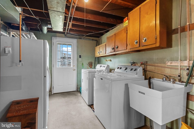 clothes washing area featuring washing machine and clothes dryer, a sink, and cabinet space